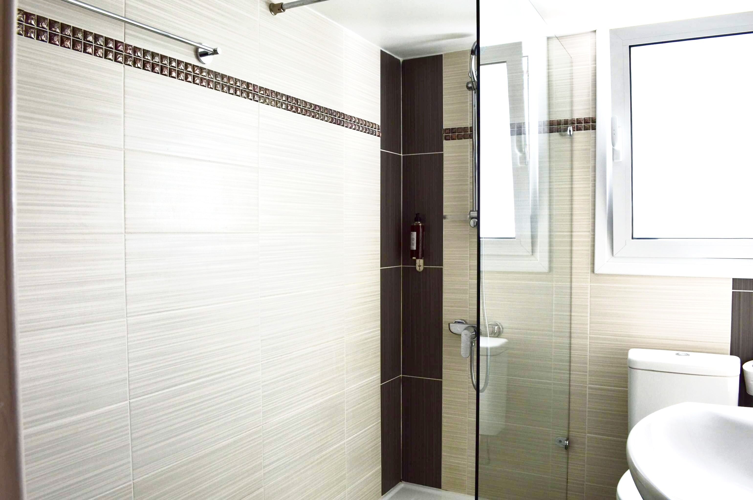 Une salle de bain moderne avec une douche à parois de verre, des toilettes blanches et un lavabo.