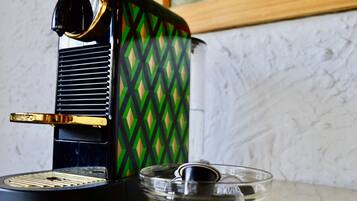 A coffee maker with a green and black diamond pattern, a clear glass carafe, and a metal spoon.