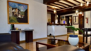 A hotel lobby with a painting on the wall, a reception desk, a vase with a plant, and a wooden ceiling. - Lordos Hotel Apartments (Egkomi)