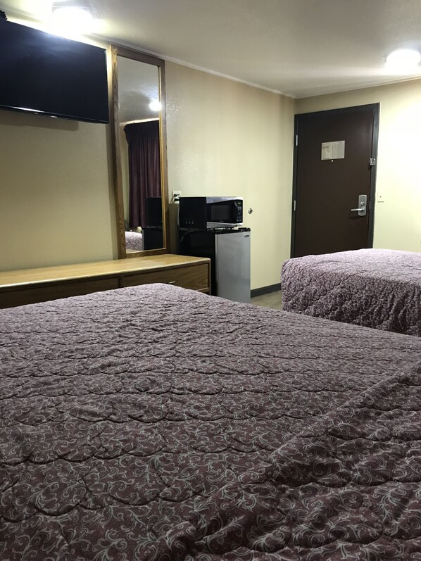 A hotel room with two beds, a small kitchenette with a microwave, a refrigerator, and a mirror. - Memphis Inn (Memphis)