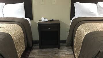 A hotel room with two beds, a small nightstand with a phone, and a wooden floor.