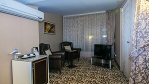 A hotel room with a patterned carpet, a television, a desk with a coffee maker, and a chair. - For You Medikent Otel (Atakum)
