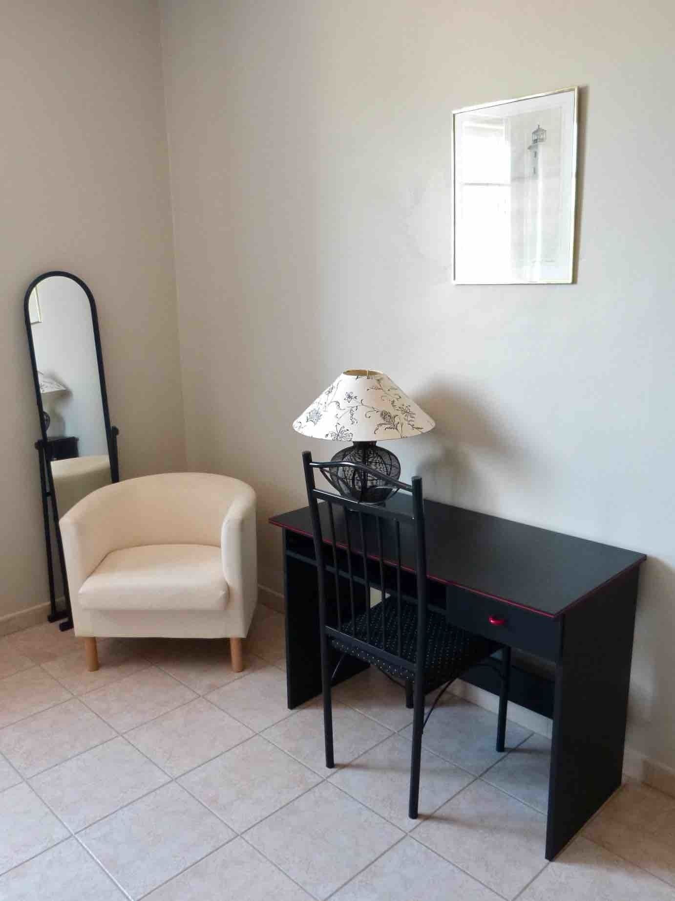 A room with a desk, chair, and a small sofa.