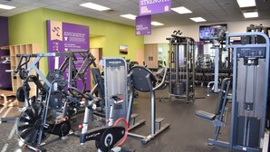 Een fitnessruimte met diverse trainingsapparaten, halterbanken en losse gewichten.