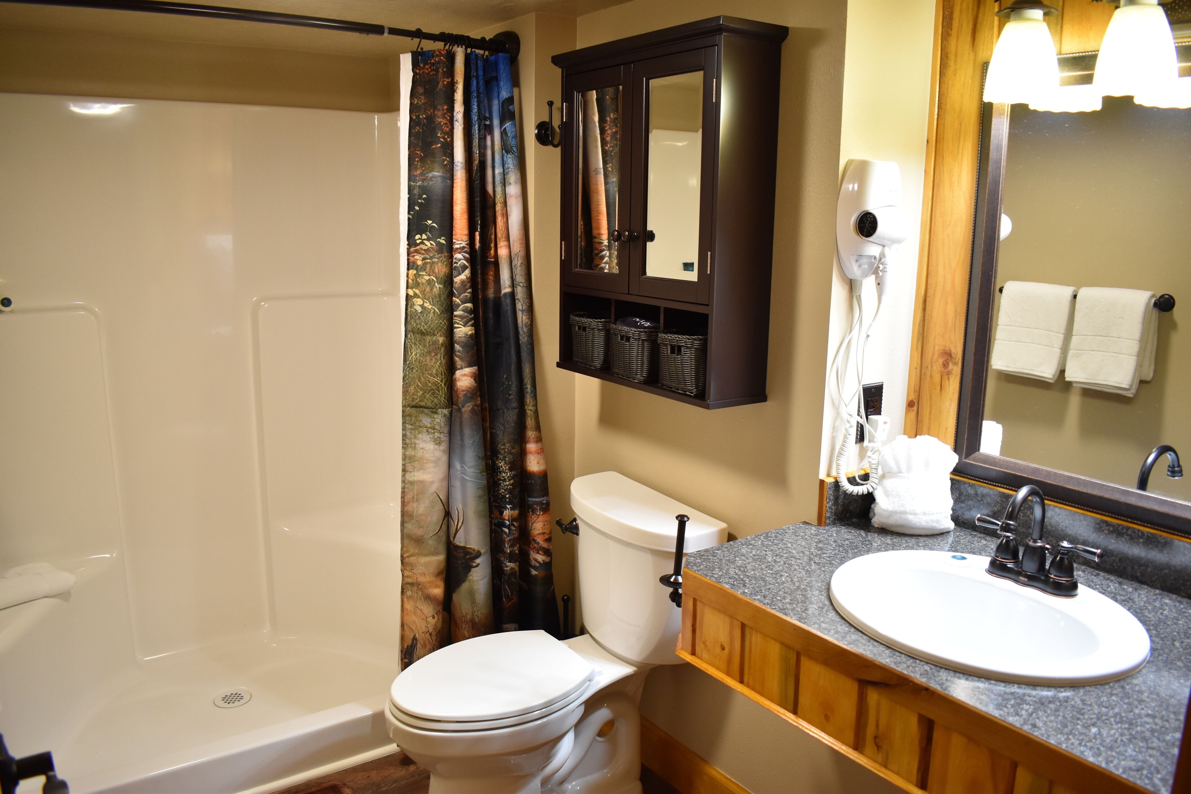 A bathroom with a shower, toilet, sink, and a cabinet with baskets.