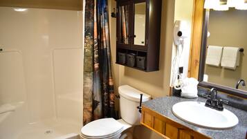 A bathroom with a shower, toilet, sink, and a cabinet with baskets.