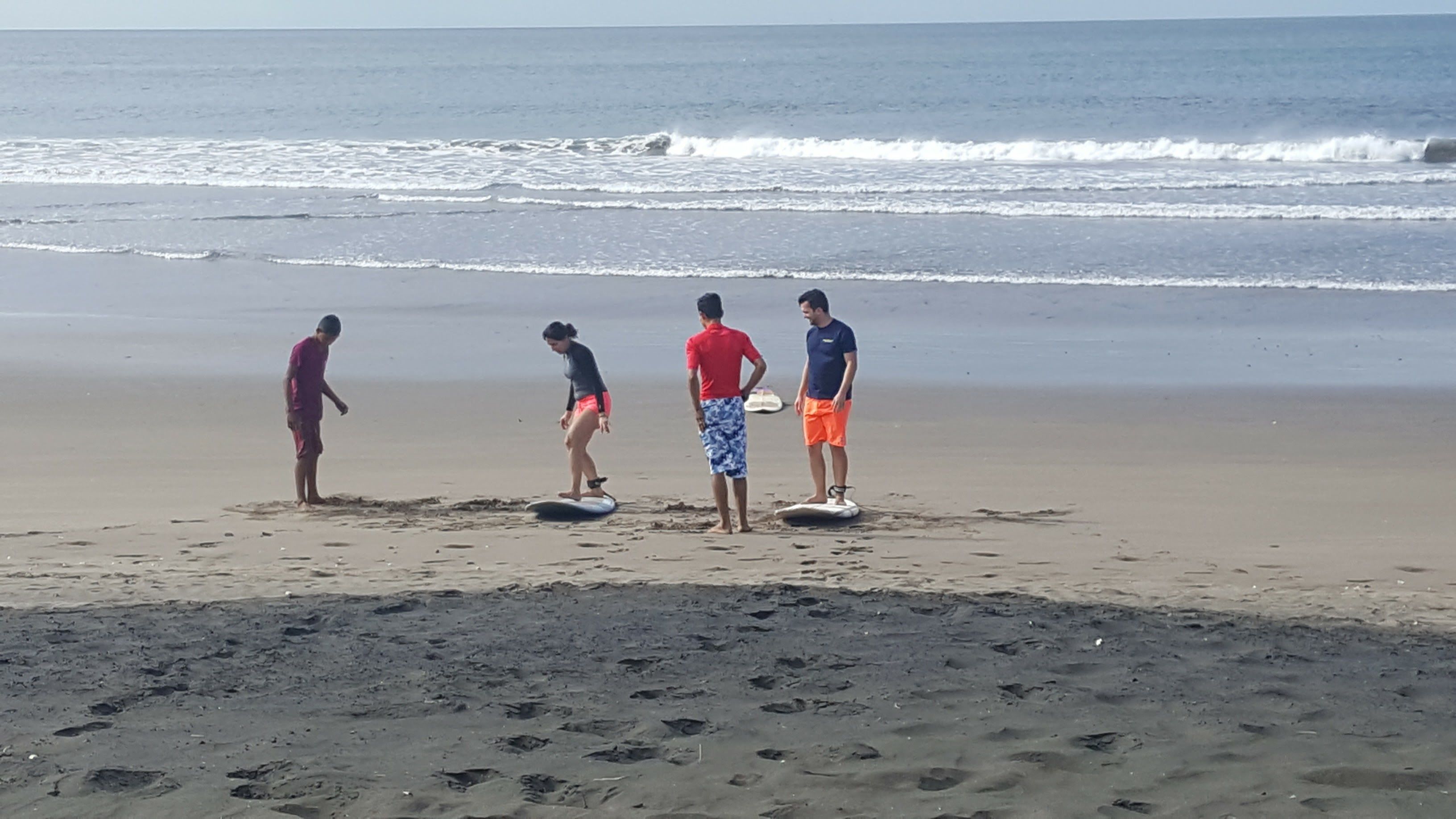 A beach with four people standing on surfboards.