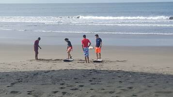 A beach with four people standing on surfboards.