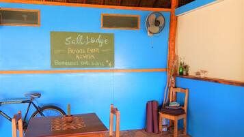 A rustic room with a thatched roof, a chalkboard sign, wooden furniture, and a bicycle.