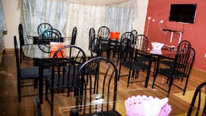 A dining area with a glass table surrounded by black chairs, a red tablecloth, and a curtain in the background. - Skyways Hotel (Bortianor)