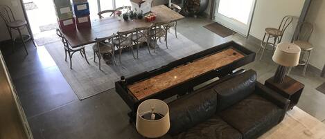 A modern living room with a shuffleboard table, a sofa, and a fireplace.