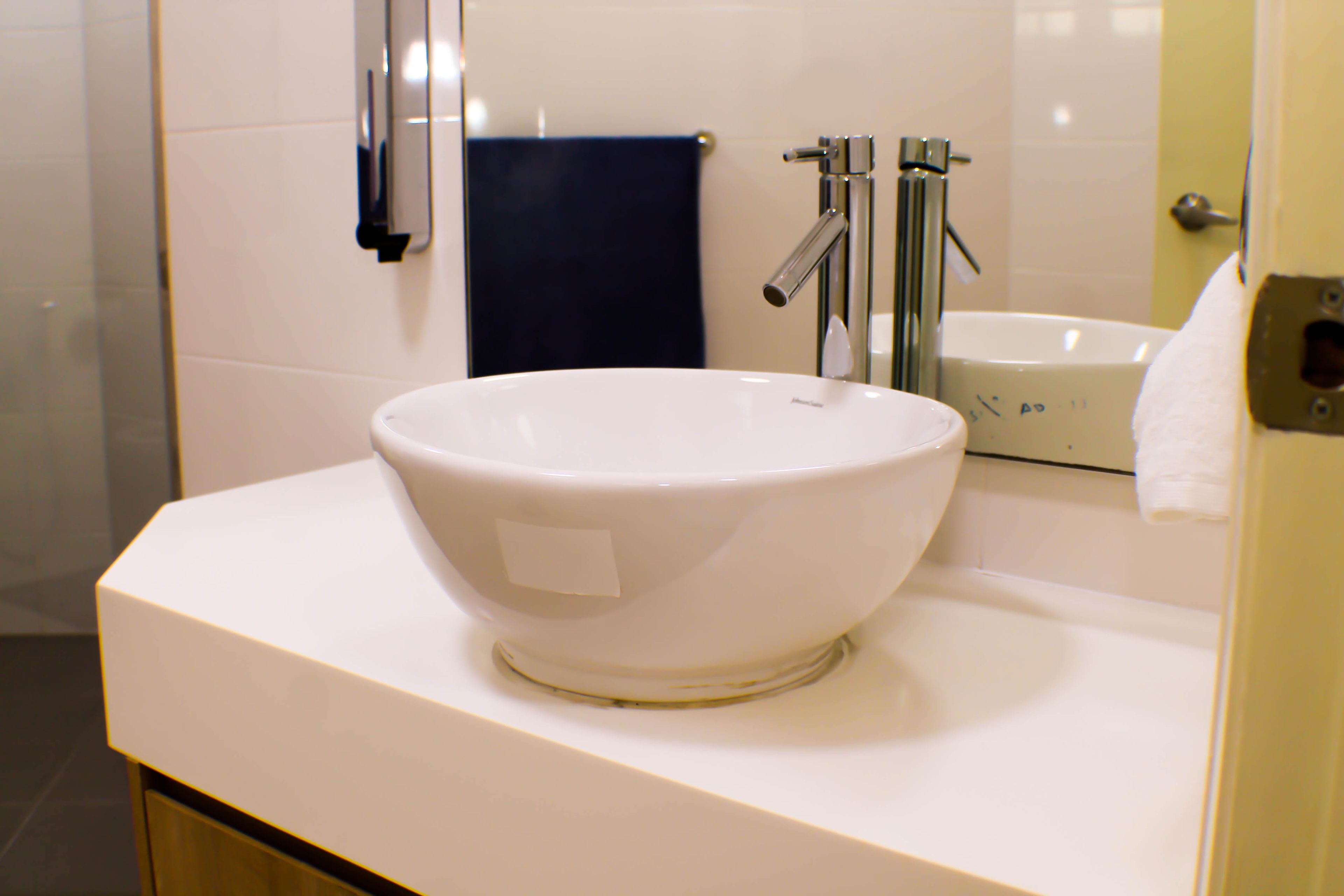 A white bathroom sink with a large bowl, a faucet, and a mirror above it.