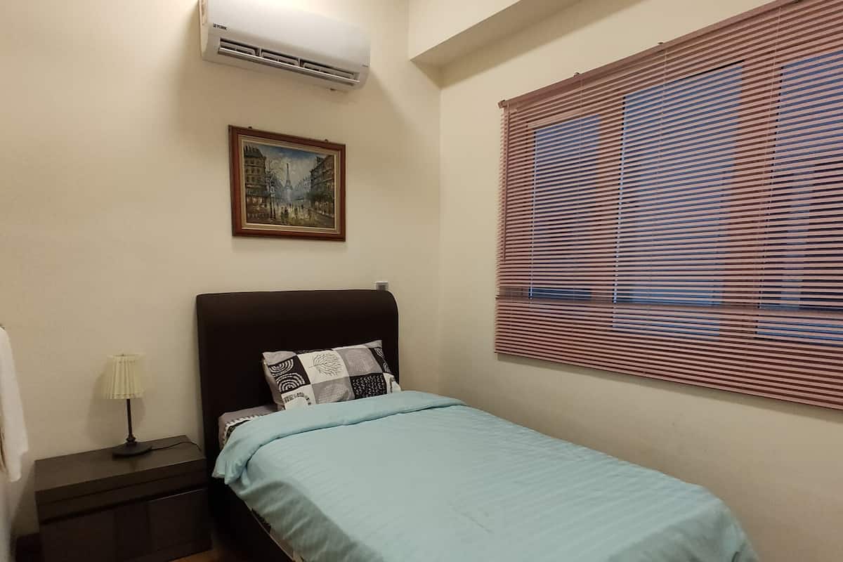 A bedroom with a bed, a nightstand, an air conditioner, a ceiling fan, a window with blinds, and a painting on the wall.