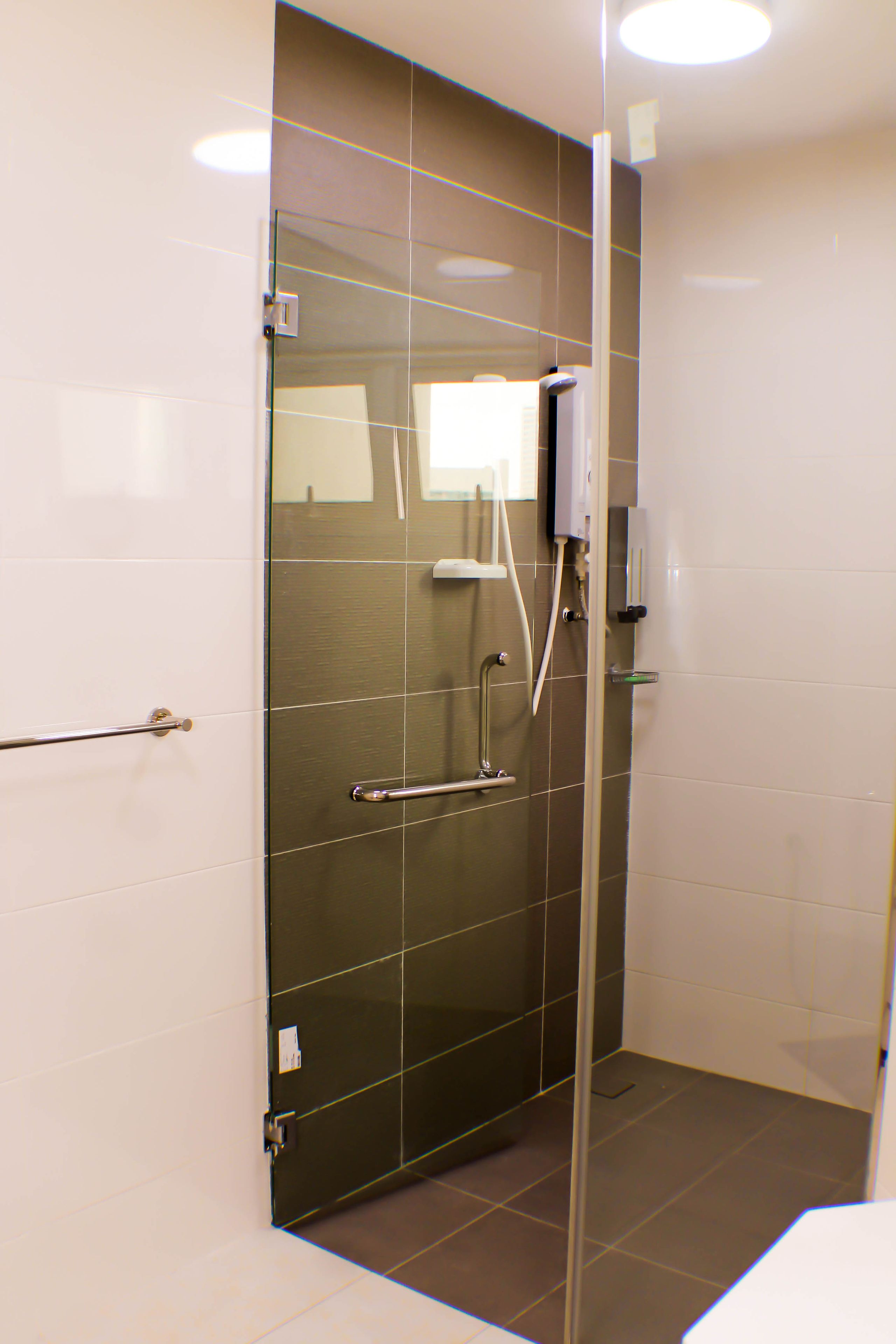 Een moderne badkamer met een glazen douchecabine, een handdroger en een handdoekhouder.