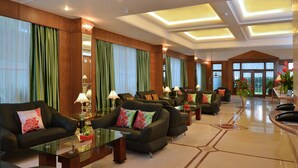 Un'ampia hall con diverse zone salotto, grandi finestre e una reception.