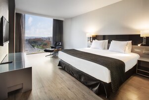 Et moderne hotelværelse med en stor seng, et skrivebord og udsigt over byen.
