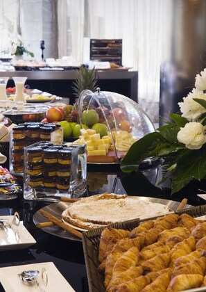 Un buffet proposant une variété de plats, notamment des pâtisseries, des fromages et des fruits.