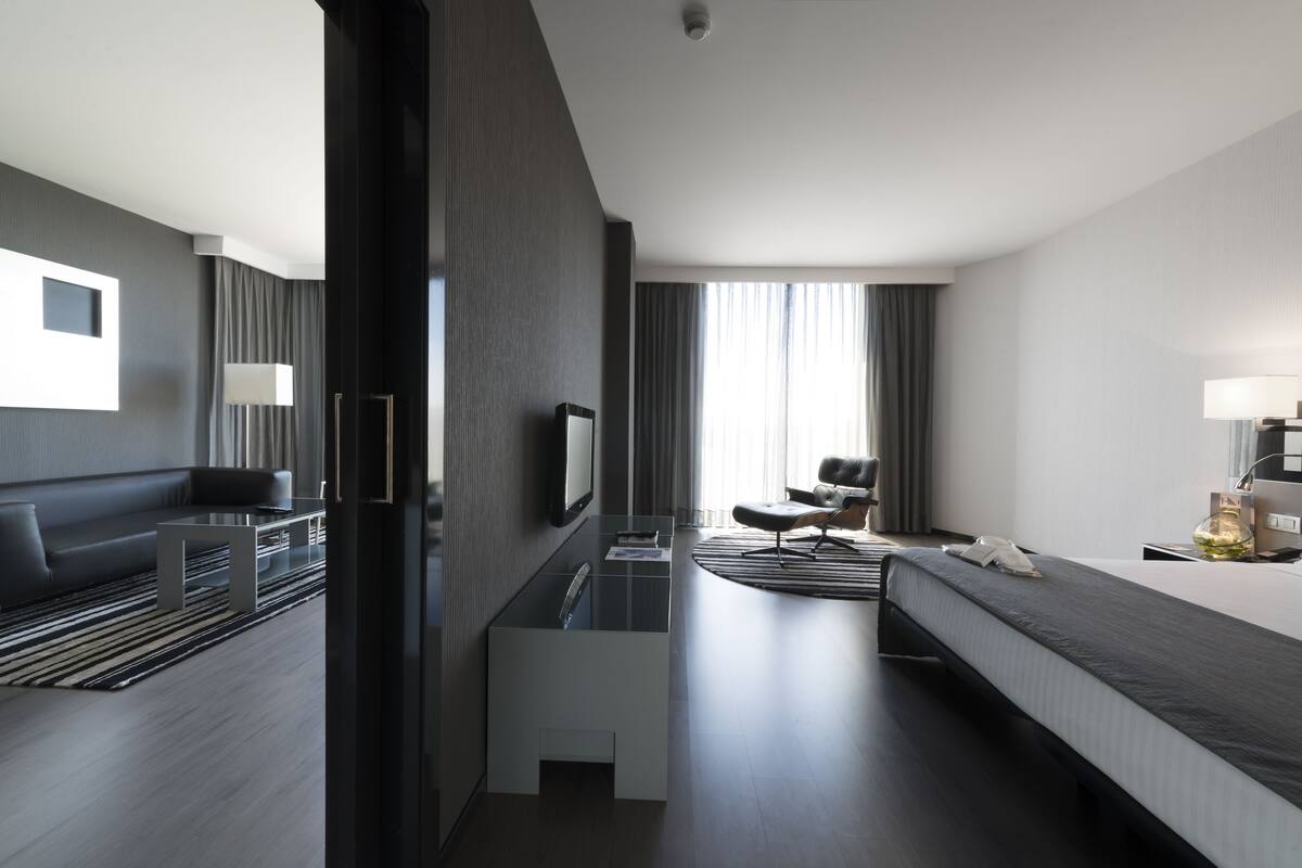 Una habitación de hotel moderna con sofá, cama, escritorio y televisor.