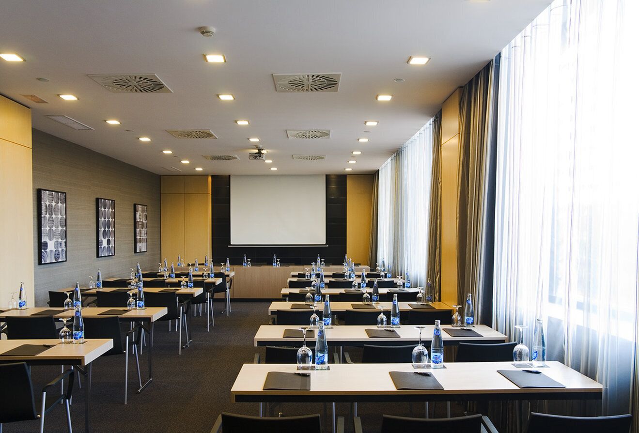 A conference room with multiple tables, chairs, and a projector screen.
