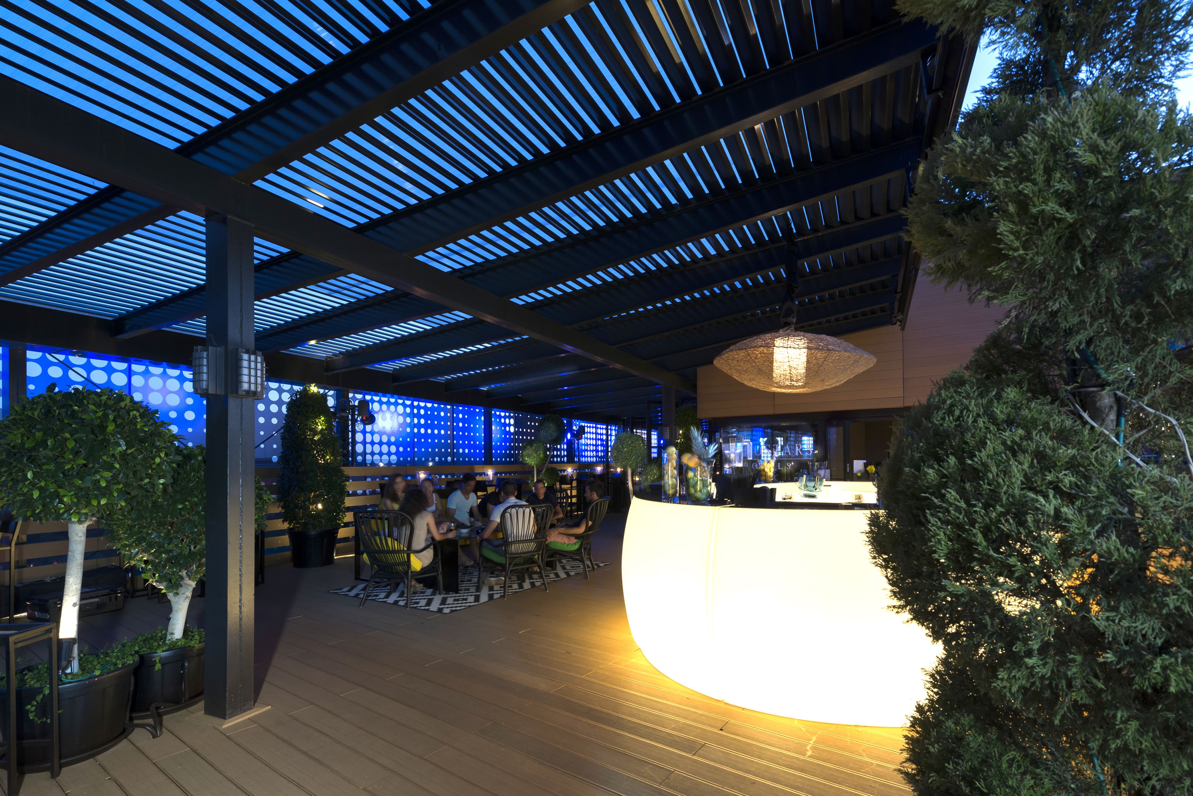 An indoor area with a curved reception desk, wooden flooring, and a ceiling with blue lighting.