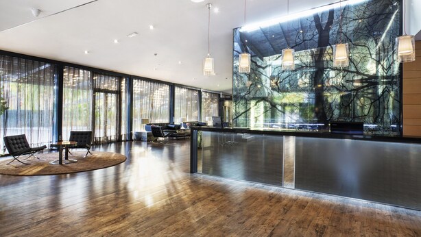 Un vestíbulo moderno con piso de madera, ventanas amplias y una recepción.