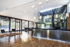 Un hall d’entrée moderne avec un plancher en bois, de grandes fenêtres et un comptoir de réception.