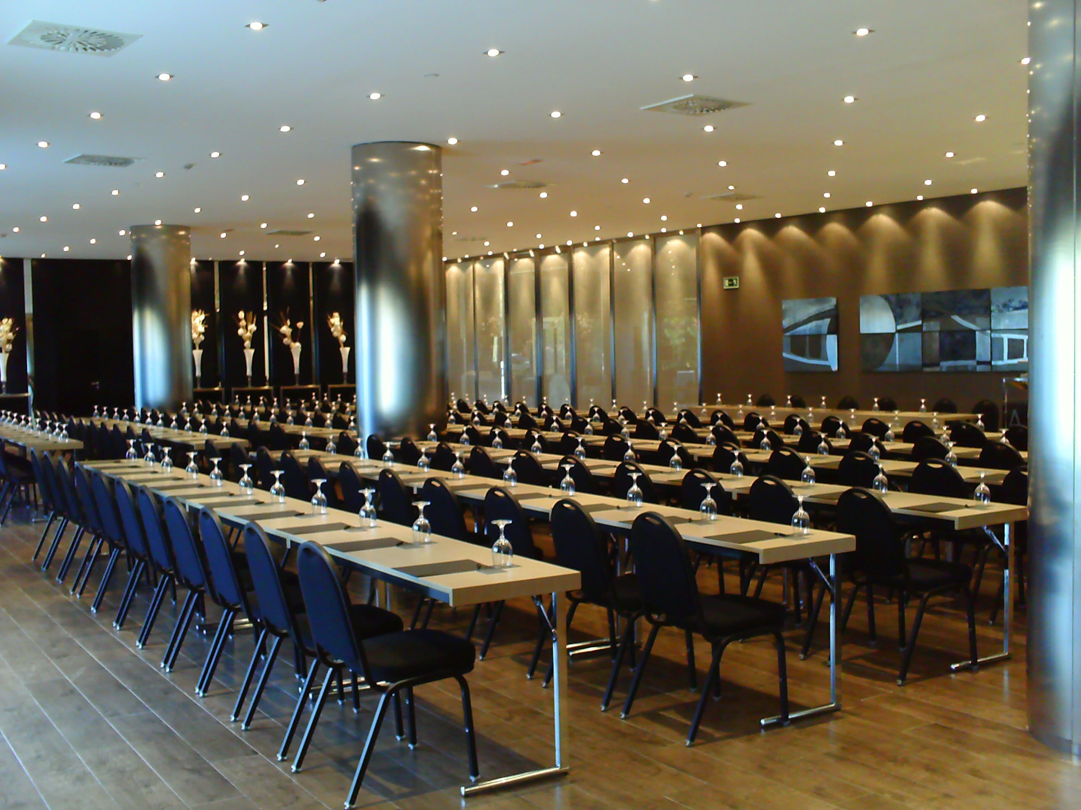 A conference room with rows of tables and chairs, equipped with water glasses and nameplates.