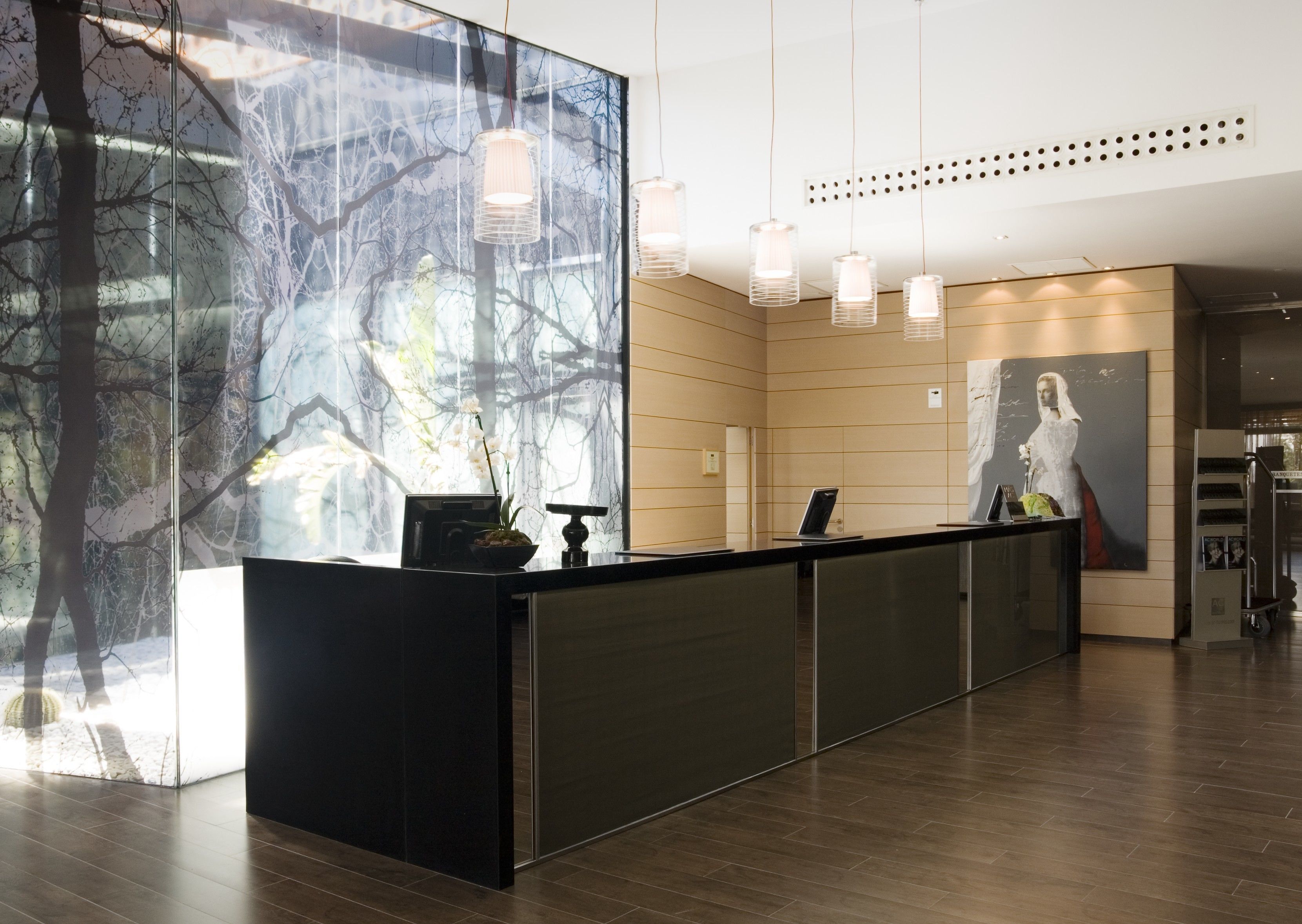 Una reception dal design moderno, un'ampia finestra con vista su alberi e un poster appeso al muro.