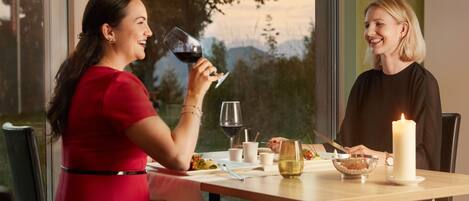 Two people dining at a table with a candle, wine glasses, and a bowl of nuts.