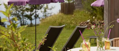 Un espace extérieur aménagé avec deux chaises, une table et des parasols violets.