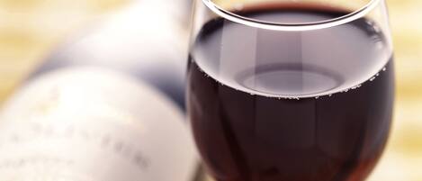 A bottle of wine, a glass of red wine, and a wine opener on a table.