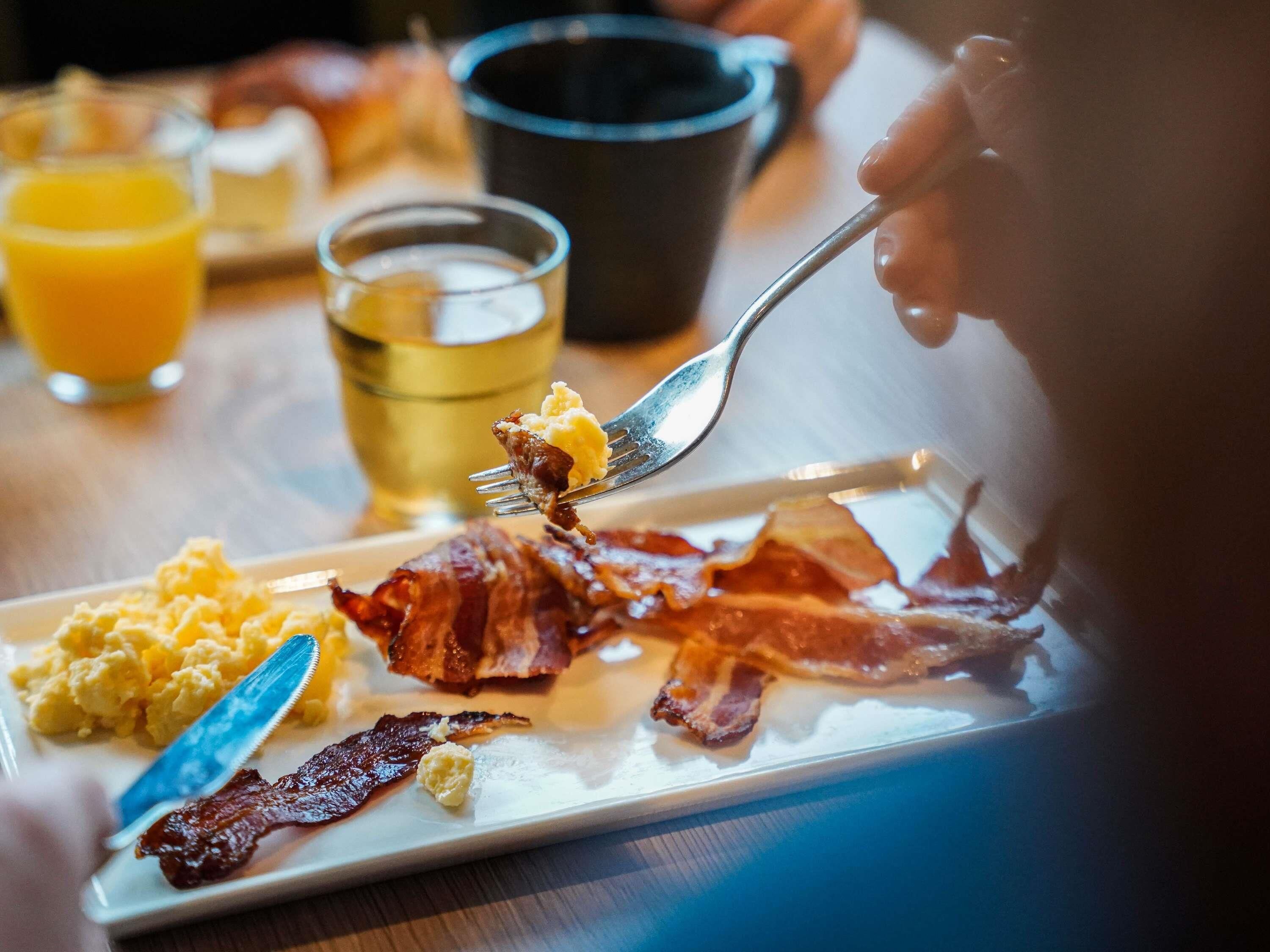 A breakfast plate with scrambled eggs, bacon, and butter.