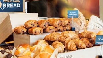 Une vitrine de boulangerie présentant différents types de pains et de viennoiseries, notamment des croissants et des pains au chocolat.