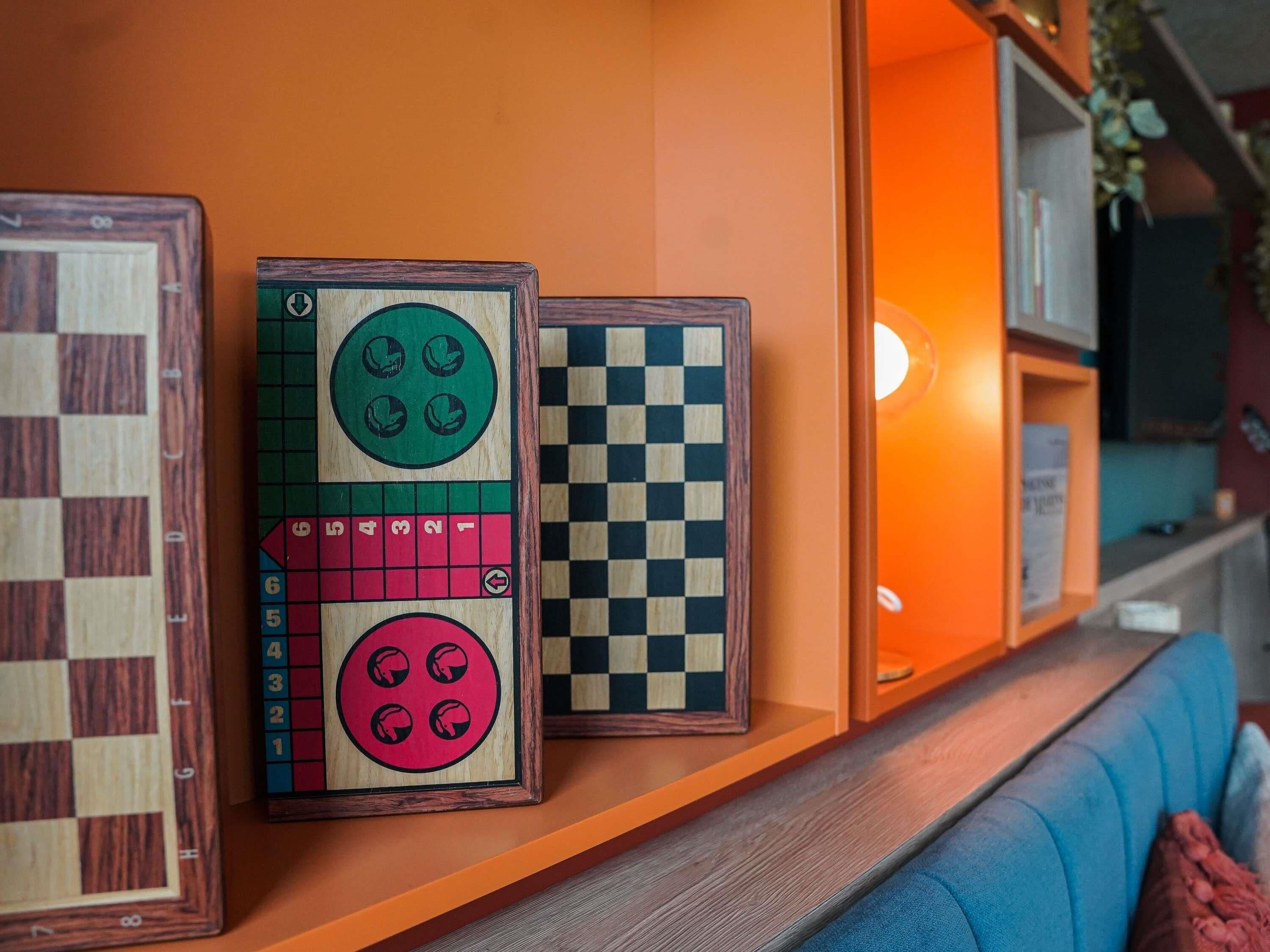 Un tablero de ajedrez y dos juegos de mesa enmarcados sobre una estantería.