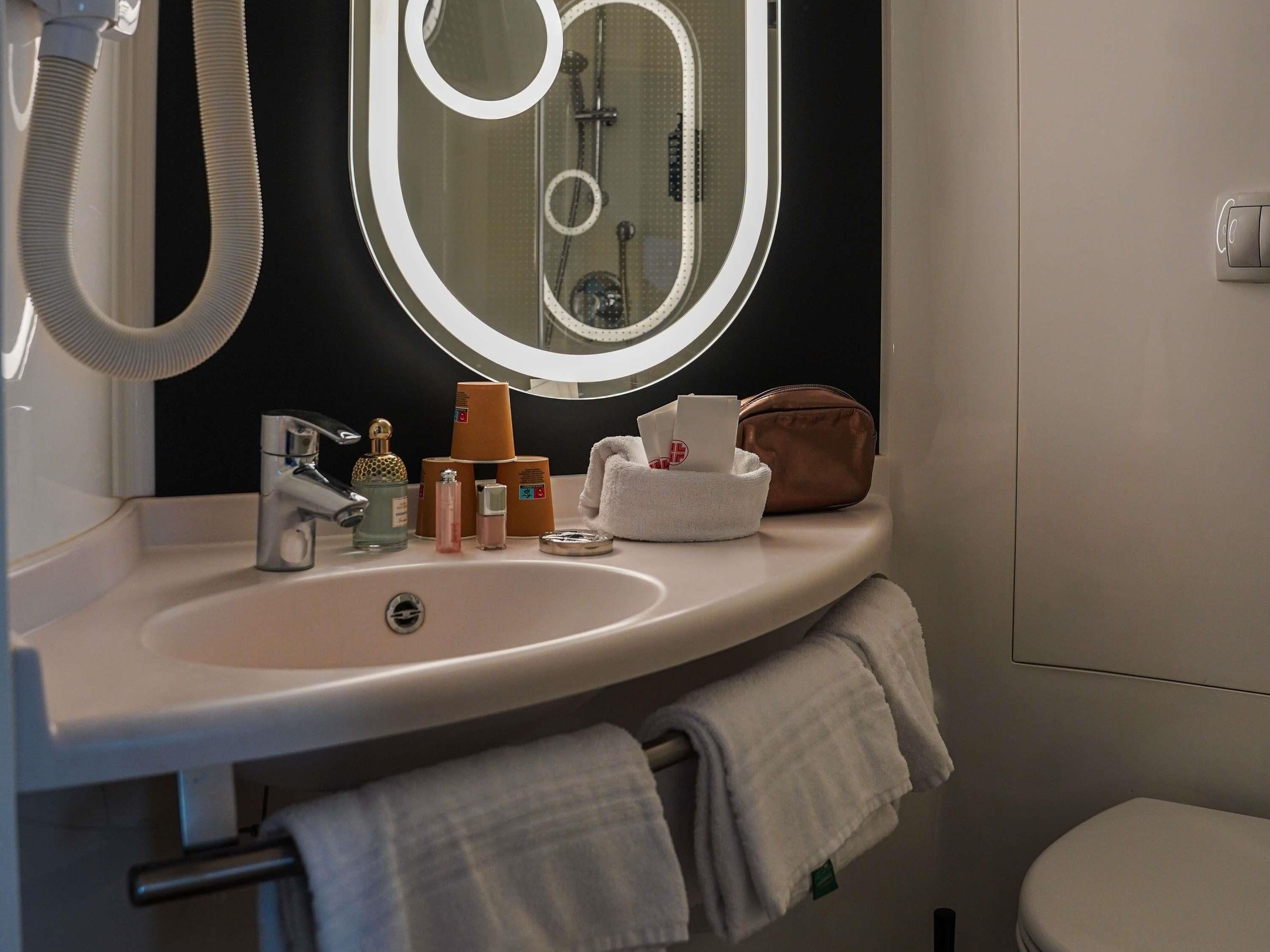 A bathroom with a sink, mirror, and toiletries.