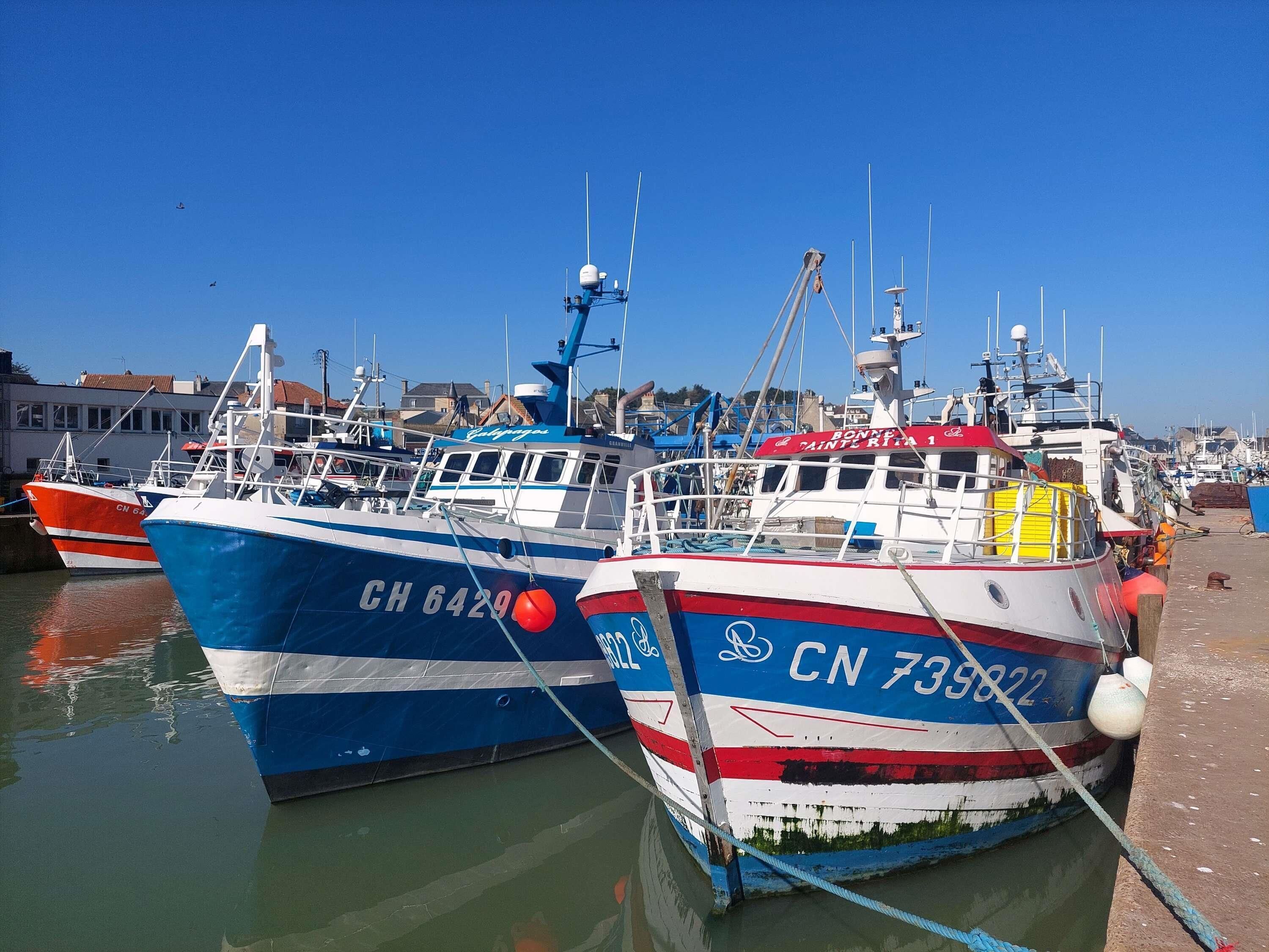 A harbor with several boats docked, featuring visible registration numbers and flags.