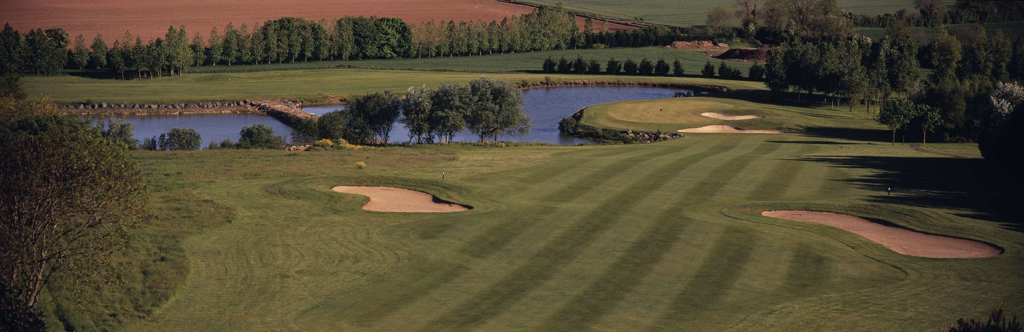 Un parcours de golf doté de bunkers, d’obstacles d’eau et d’un étang.