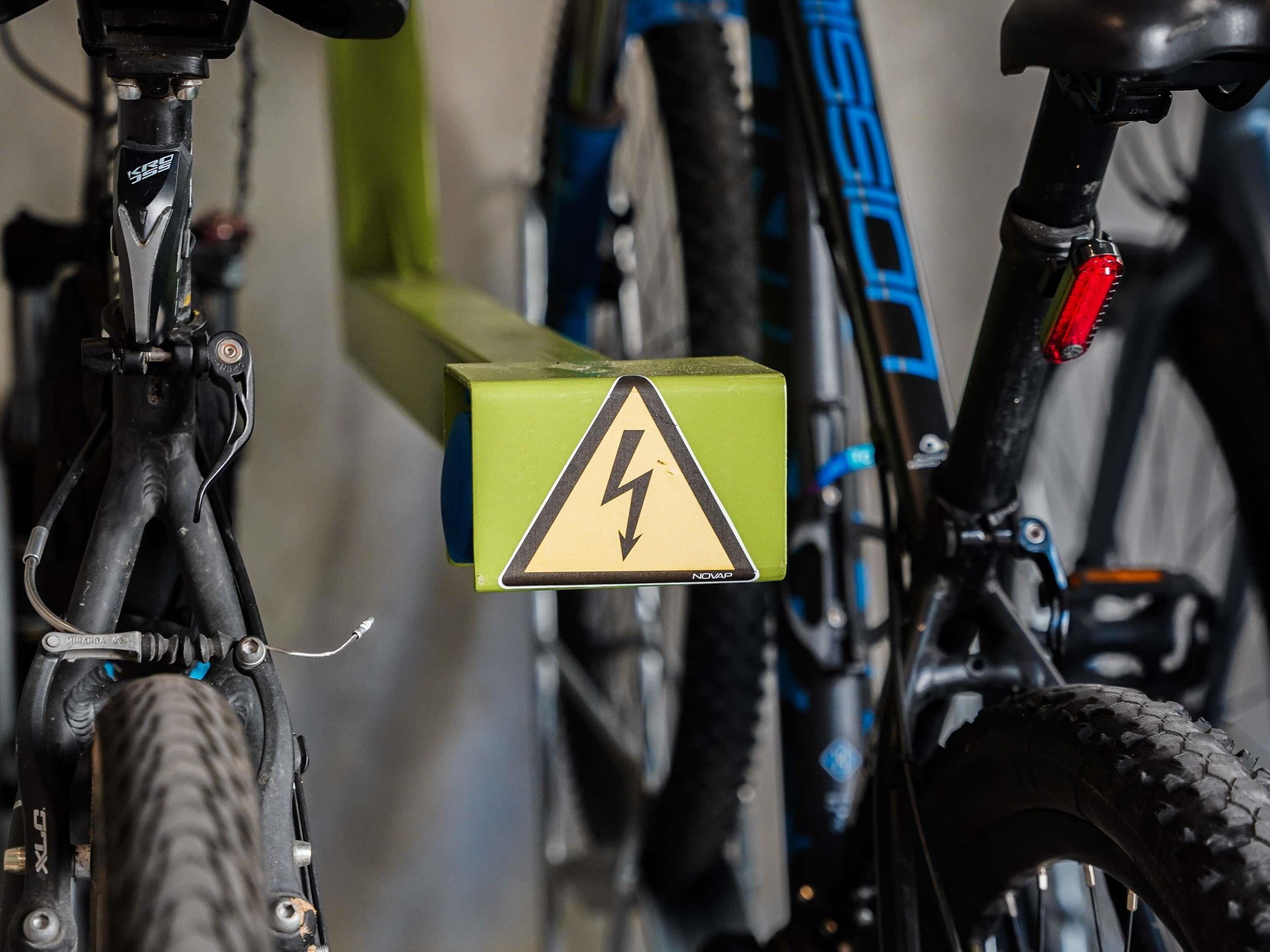 Un primo piano di una bicicletta con un cestino verde con un simbolo a forma di fulmine, probabilmente un'area di riparazione o manutenzione.