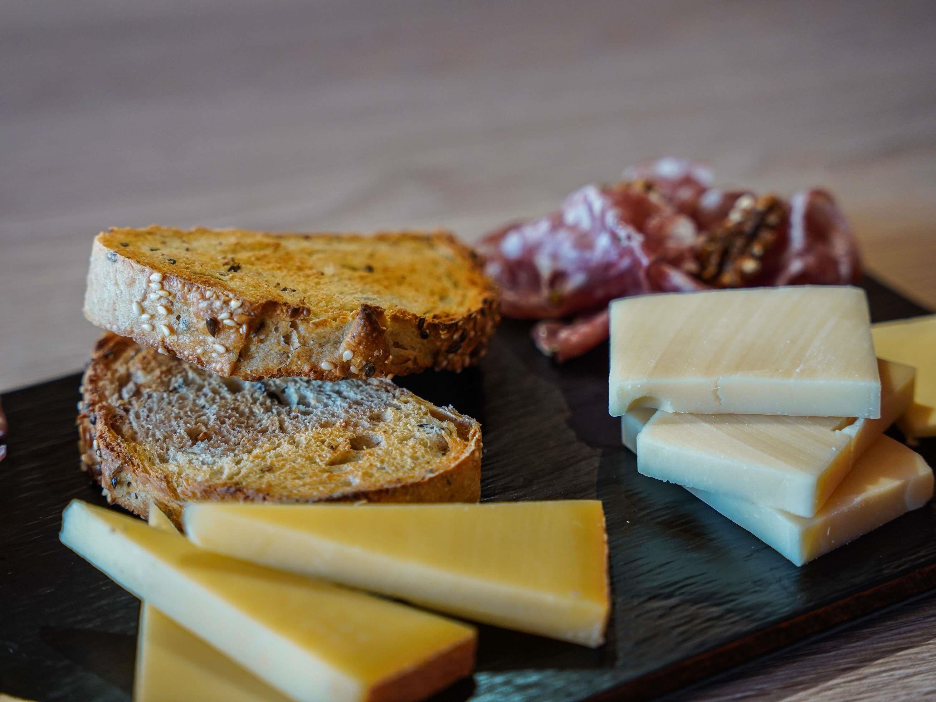 Een charcuterieplank met sneetjes brood, verschillende kazen en vleeswaren.