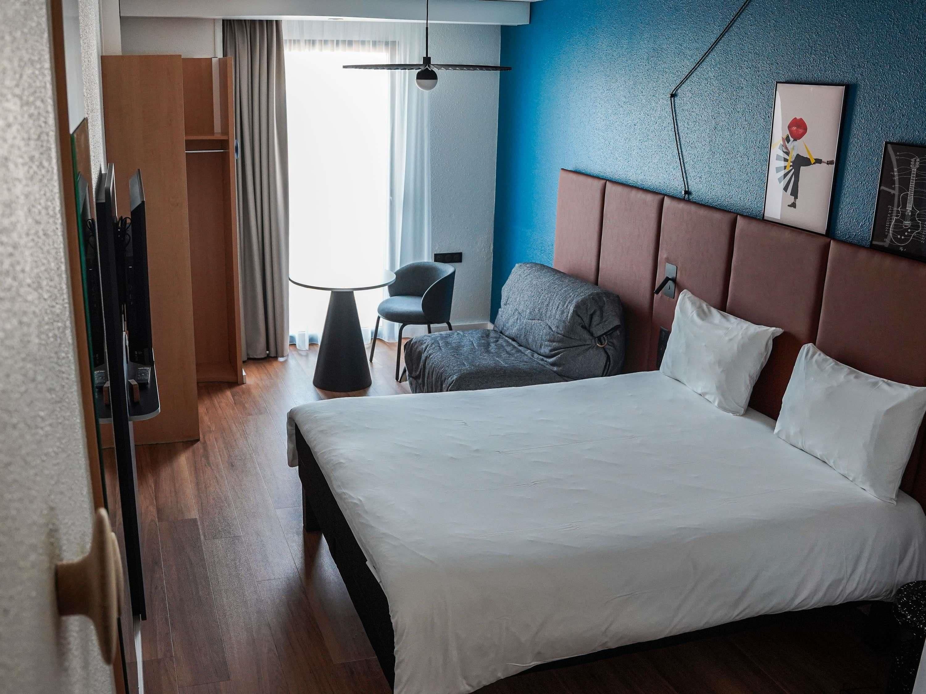 Une chambre d’hôtel avec un lit, une chaise, une table et une armoire.