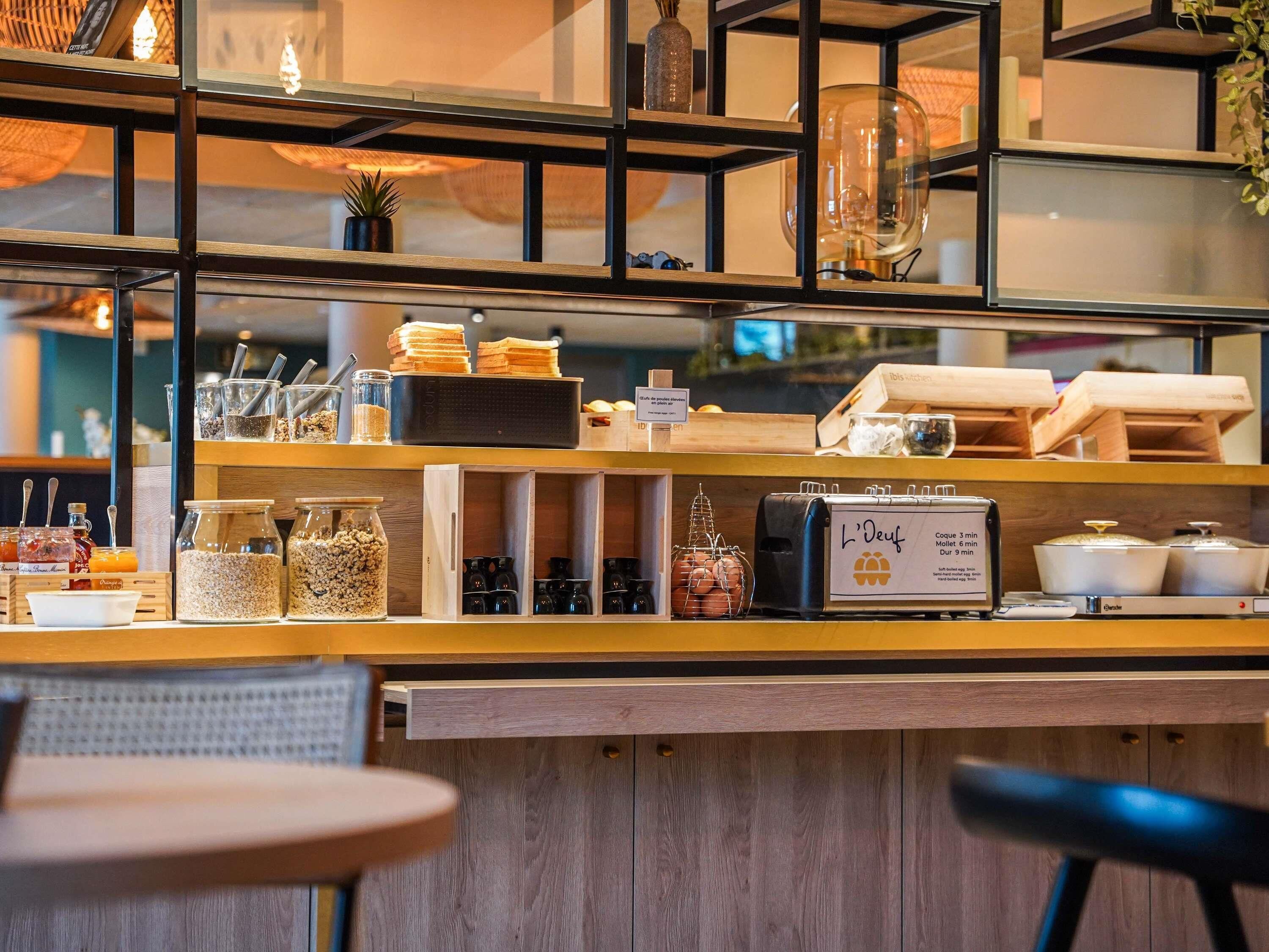 A breakfast bar with various food items, a coffee machine, and a sign indicating coffee and tea options.