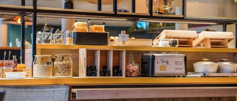 A breakfast bar with various food items, a coffee machine, and a sign indicating coffee and tea options.