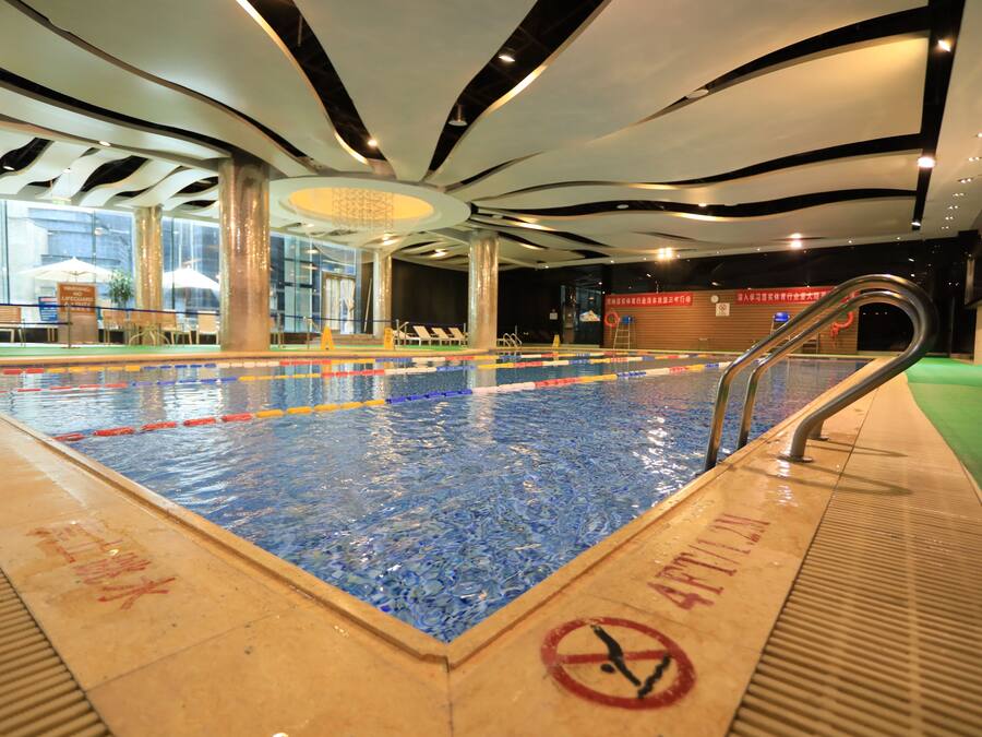 An indoor swimming pool with clear water, a no diving sign, and a lifeguard chair.