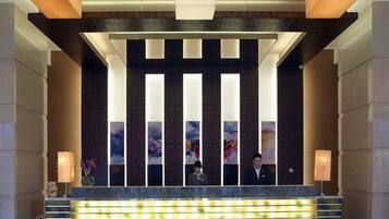 A reception area with a modern design, featuring a reception desk, vertical light panels, and a large abstract painting on the wall.