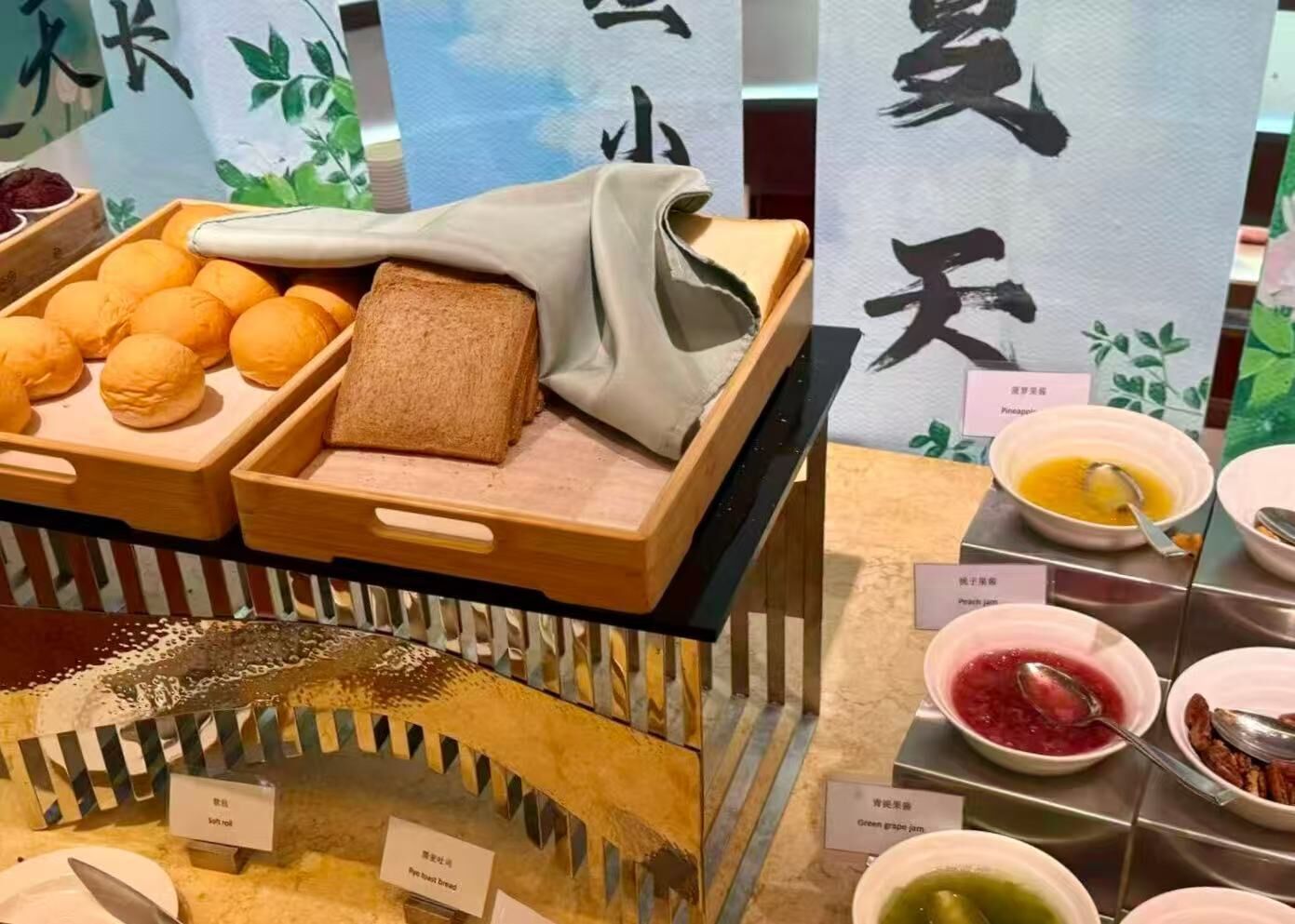A food display with bread, buns, and various condiments.