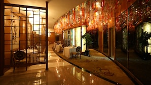 A hotel corridor with tables and chairs, a decorative glass wall, and a reflective floor. - Four Points by Sheraton Beijing, Haidian (Beijing)