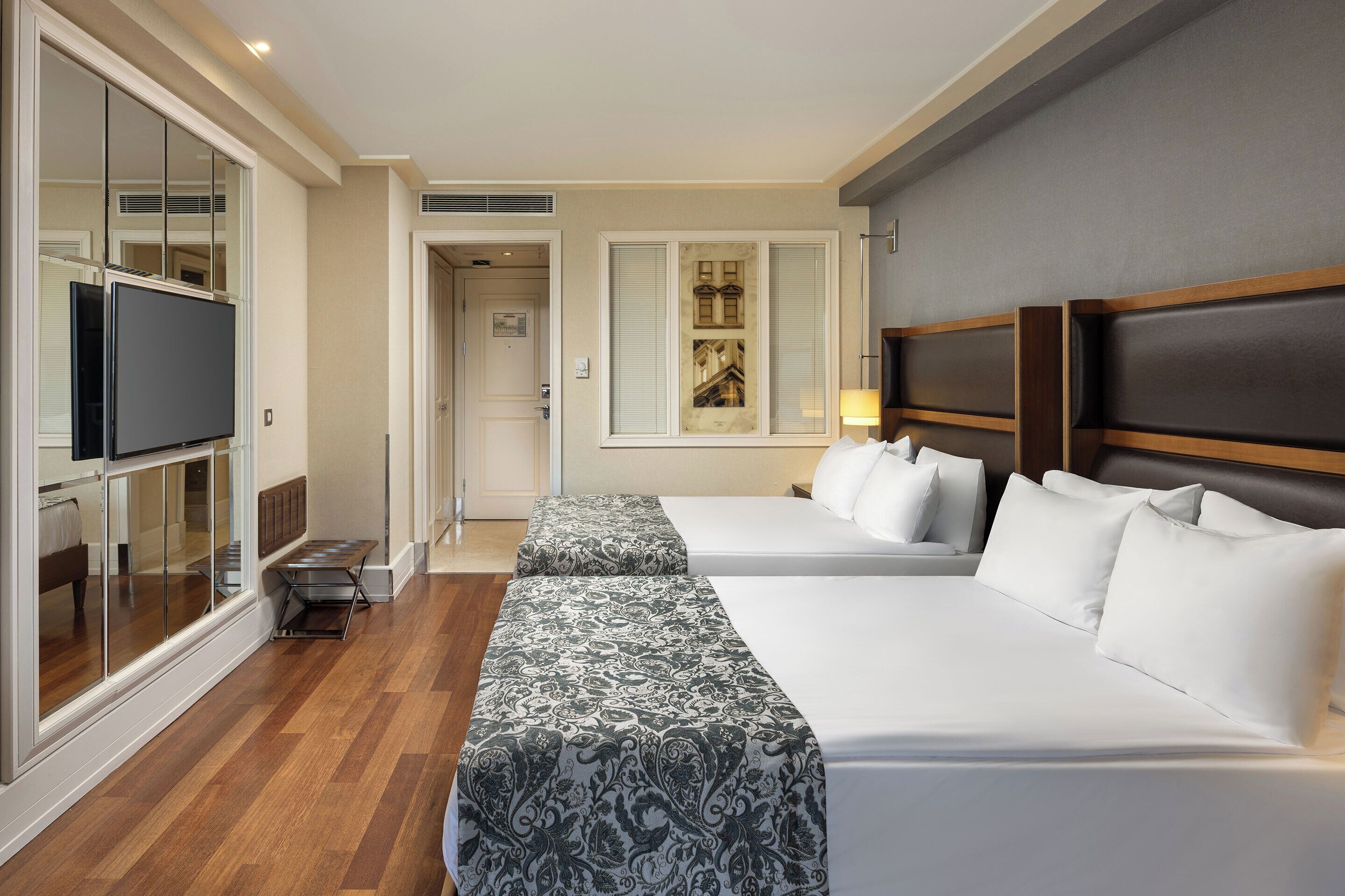 A hotel room with two beds, a TV, and a large window.