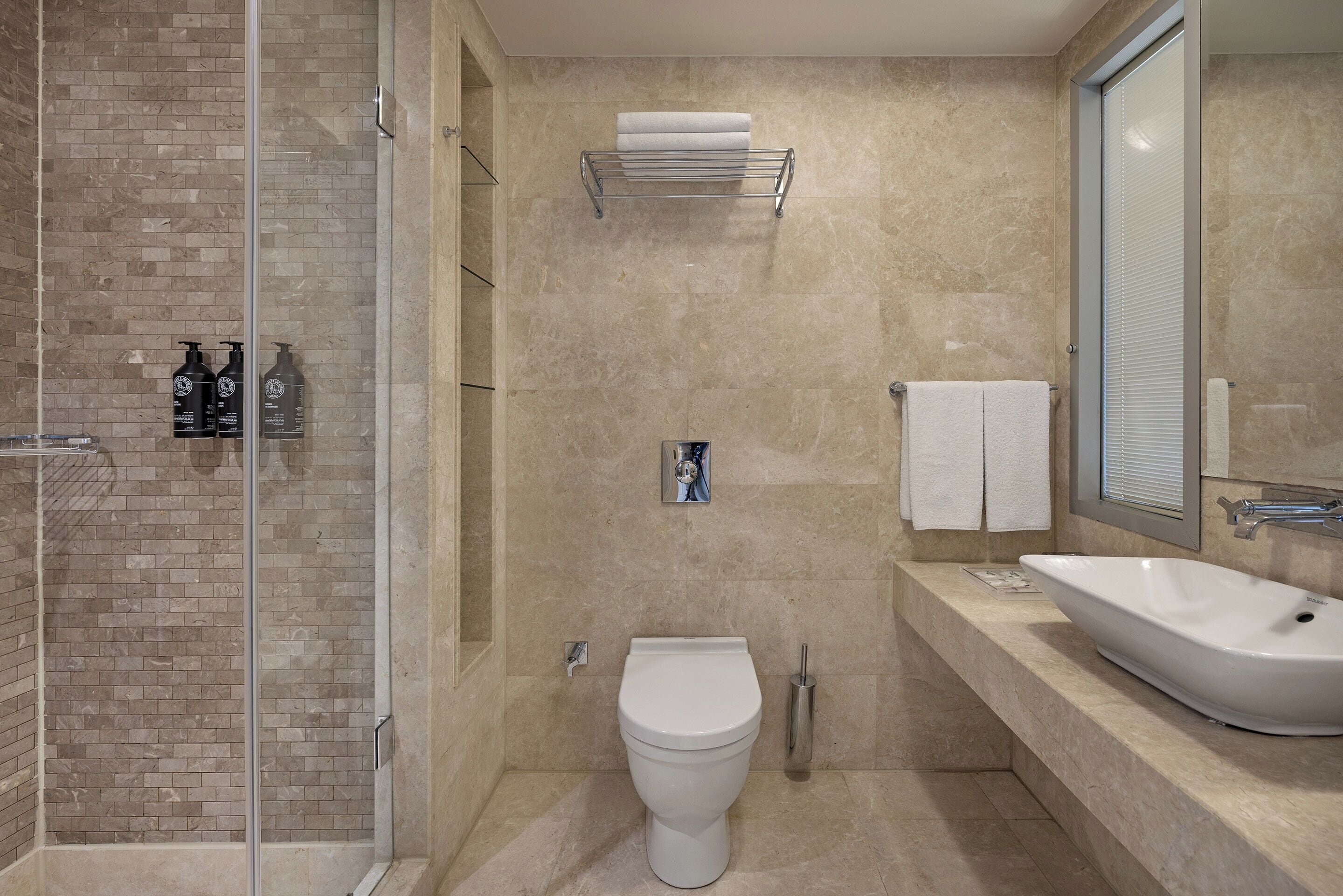 A modern bathroom with a glass-enclosed shower, a white toilet, and a large sink.