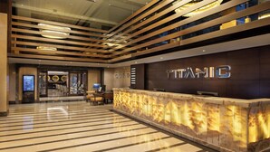 A modern hotel lobby with a reception desk, a check-in counter, and a large digital screen. - Titanic City Taksim (Istanbul)