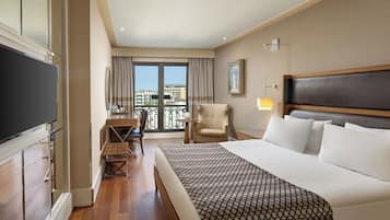 A hotel room with a large bed, a desk, a chair, and a TV.